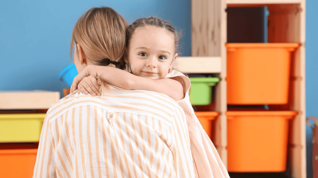 Celebrating our nannies who go above and beyond. Nanny holding a 3 year old little girl who is smiling over her shoulder